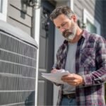 Homeowner reviewing details beside an outdoor unit to determine new ac unit cost.